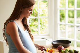 Pregnant woman chopping vegetables