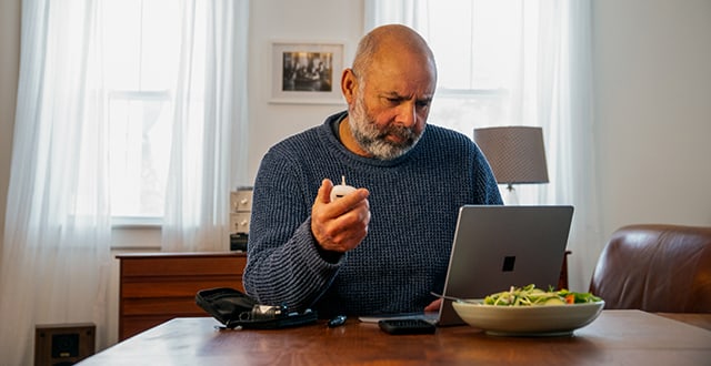 man reading tablet while eating at kitchen table