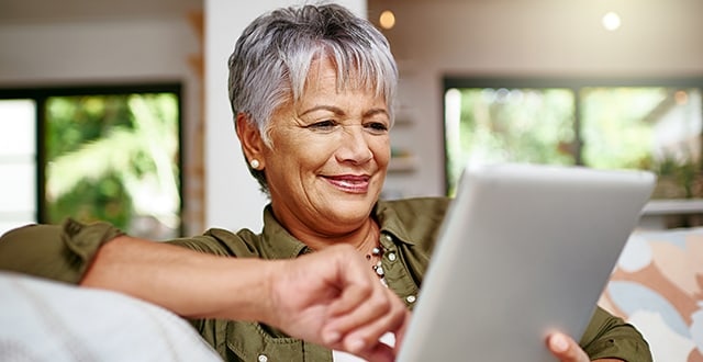 Woman sitting on couch checking her tablet